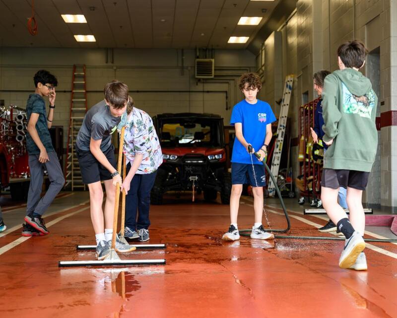 Middle School Students helping wash the firehouse floors during the Day of Giving