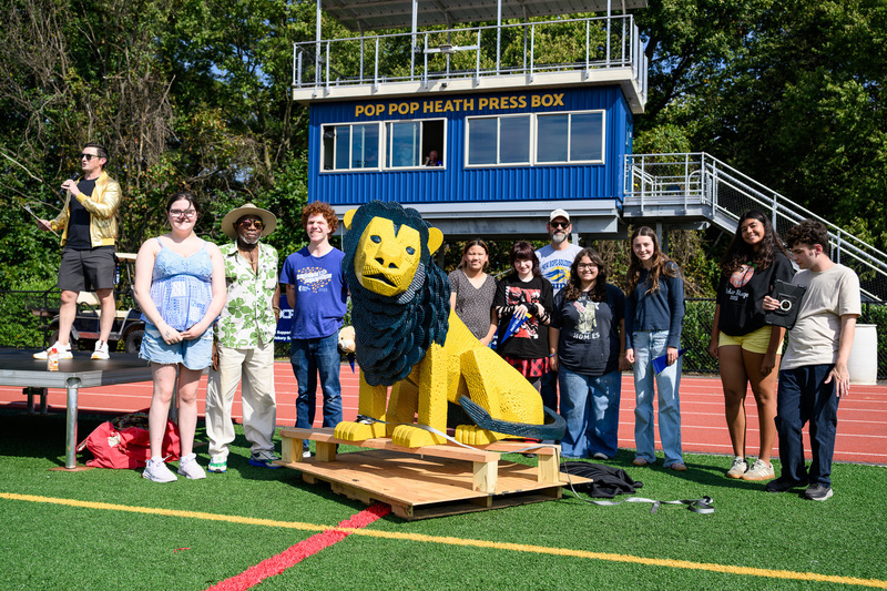 students standing with lion statue