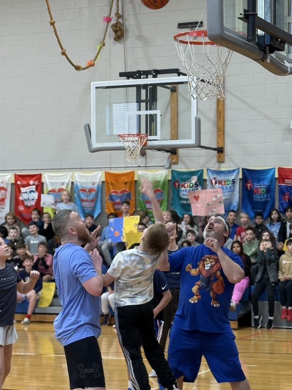 teachers and student reaching for basketball