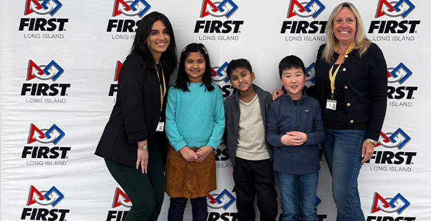 Students and teachers standing in front of FIRST banner.