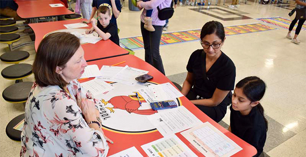 Teacher sitting at table with parent and student.