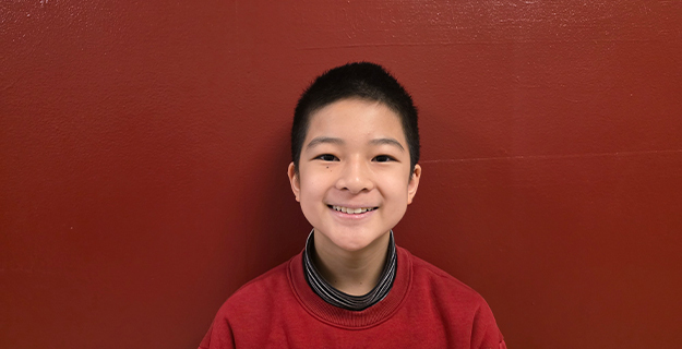 Student smiling in front of red background.