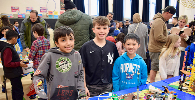Students smiling in front of table with Lego projects.