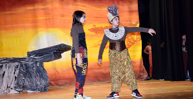 Students in costume performing on stage.