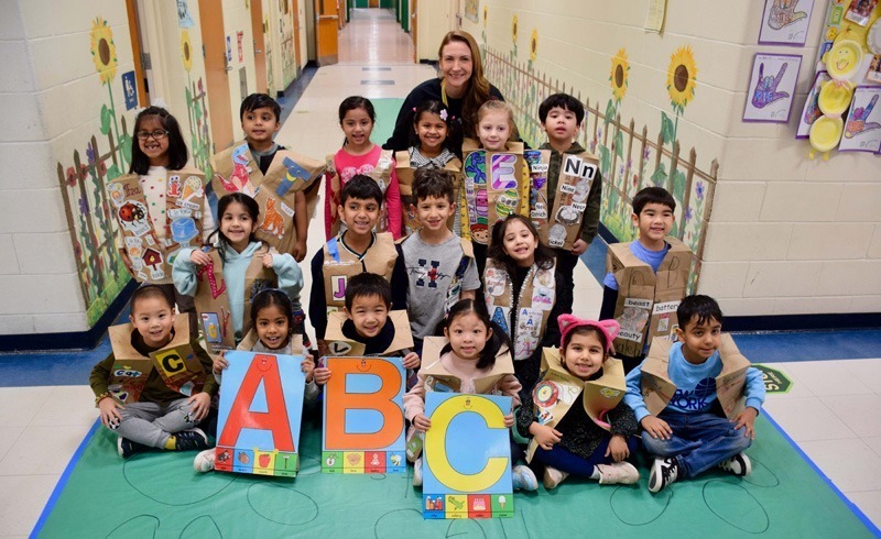 A group of young children and a teacher pose in a decorated school hallway.