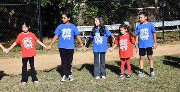 Students holding hands outside.