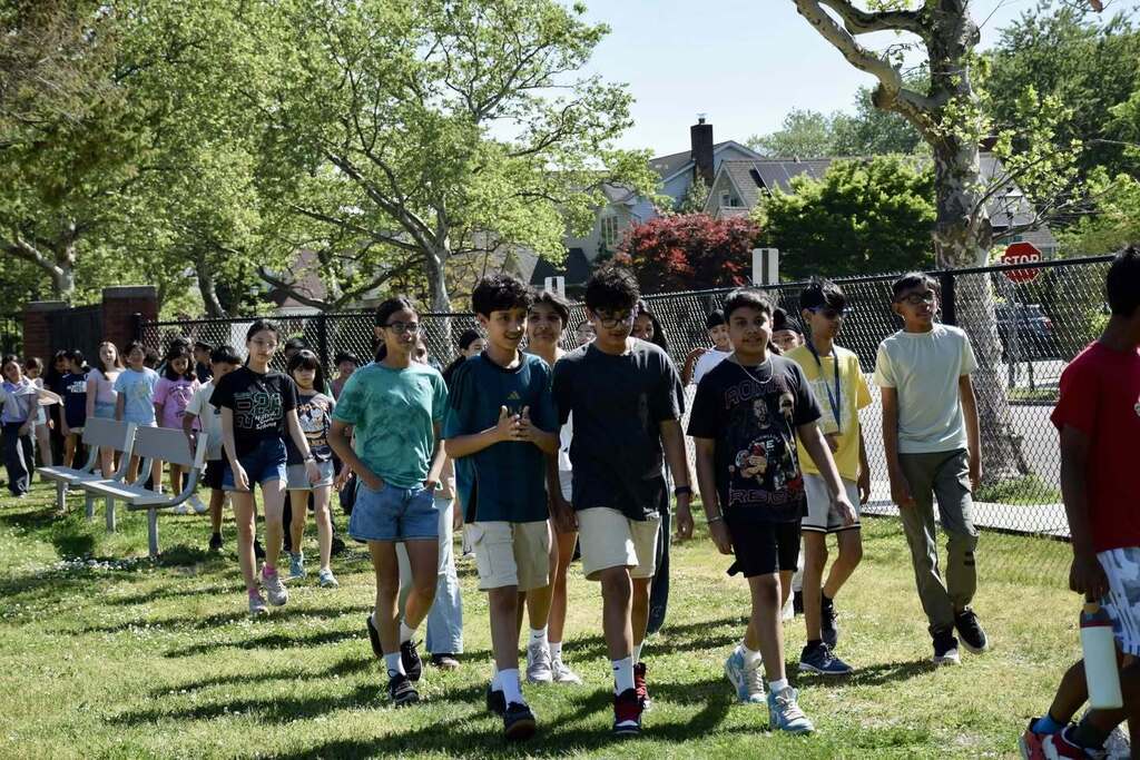 Students walking along the fence outside.