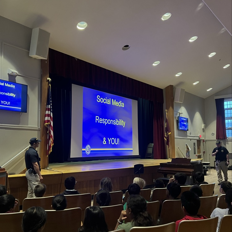 kids to an auditorium listening to an assembly