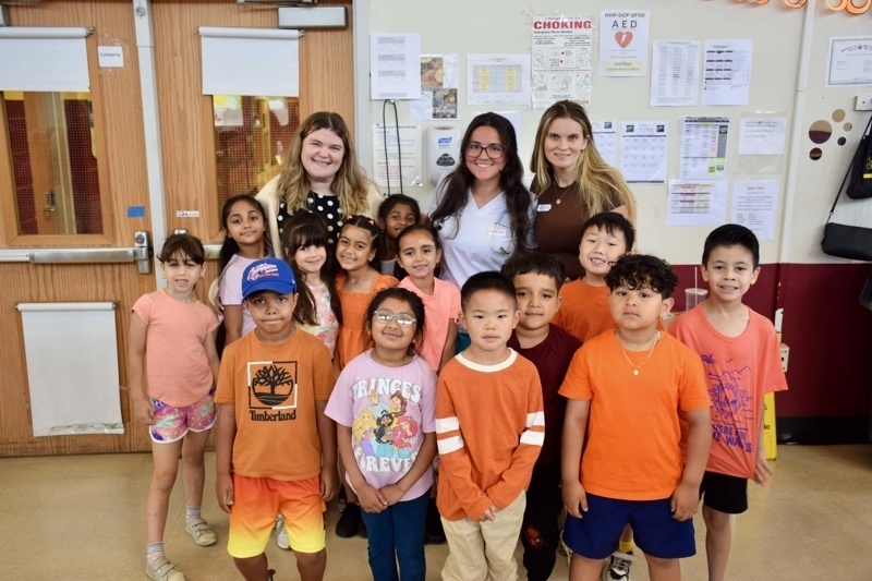 children wearing orange shirts standing indoors