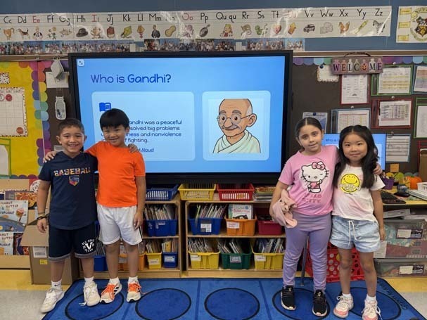 Students smiling in front of presentation on projector.