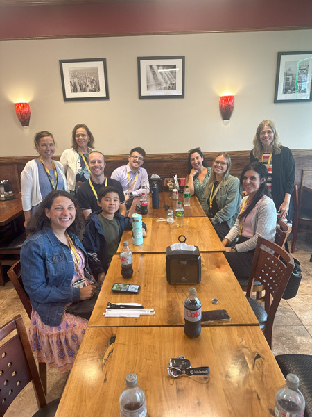 people pose at a long wood table