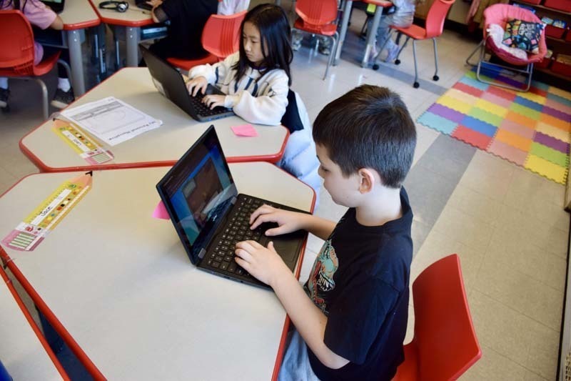 Students working on laptops in classroom.