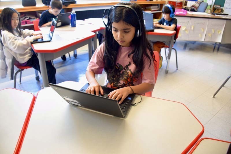 Students working on laptops in classroom.