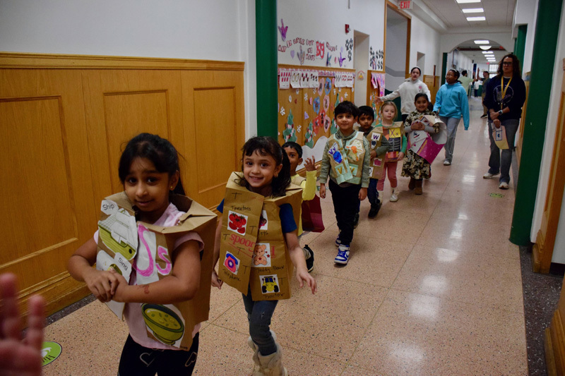 A group of young children and a teacher pose in a decorated school hallway.