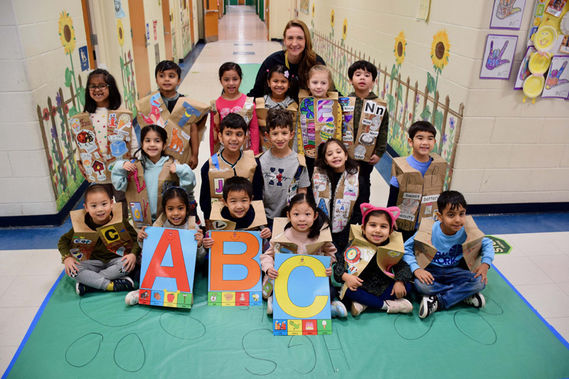 A group of young children and a teacher pose in a decorated school hallway.