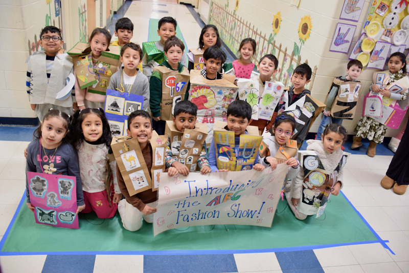 A group of young children and a teacher pose in a decorated school hallway.