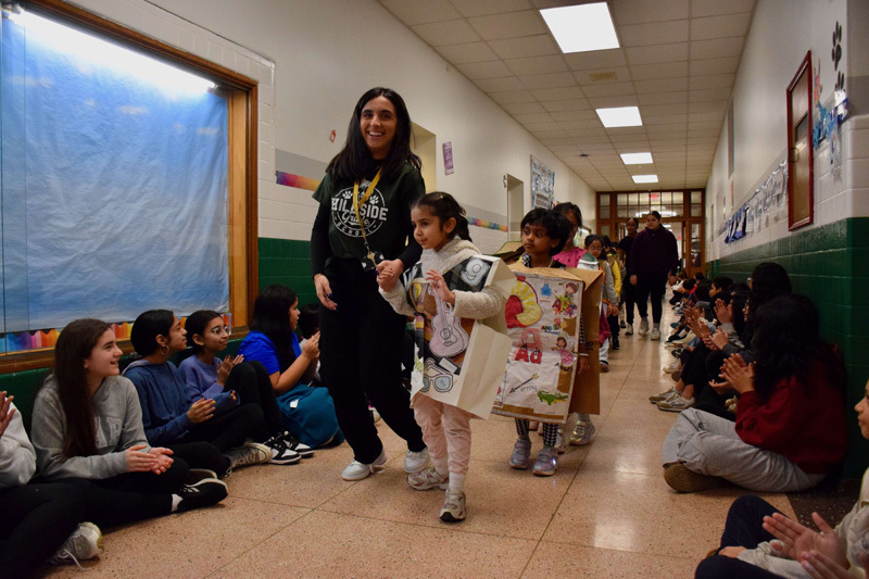A group of young children and a teacher pose in a decorated school hallway.