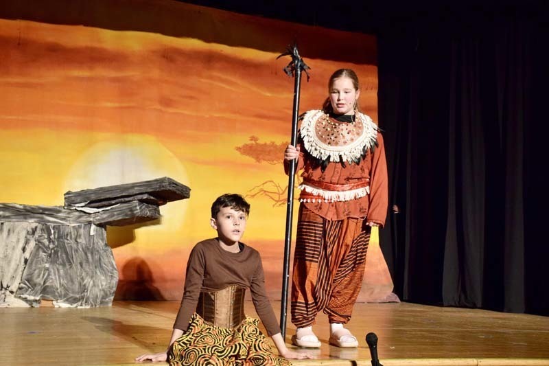 Students in costume performing on stage.