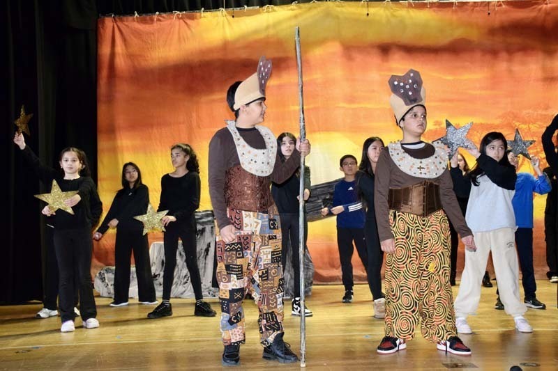 Students in costume performing on stage.