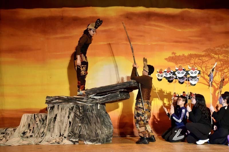 Students in costume performing on stage.