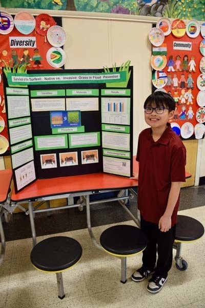 Students standing proudly in front of science fair projects.