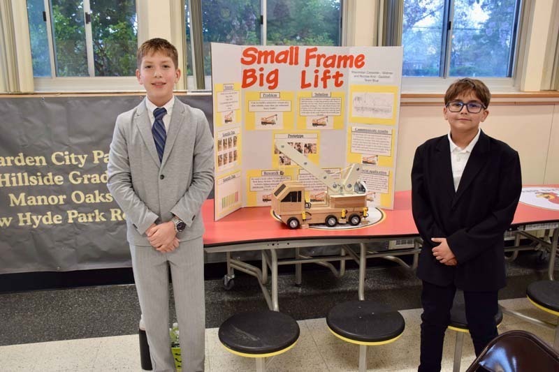 Students standing proudly in front of science fair projects.