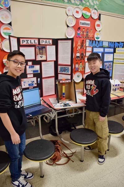 Students standing proudly in front of science fair projects.