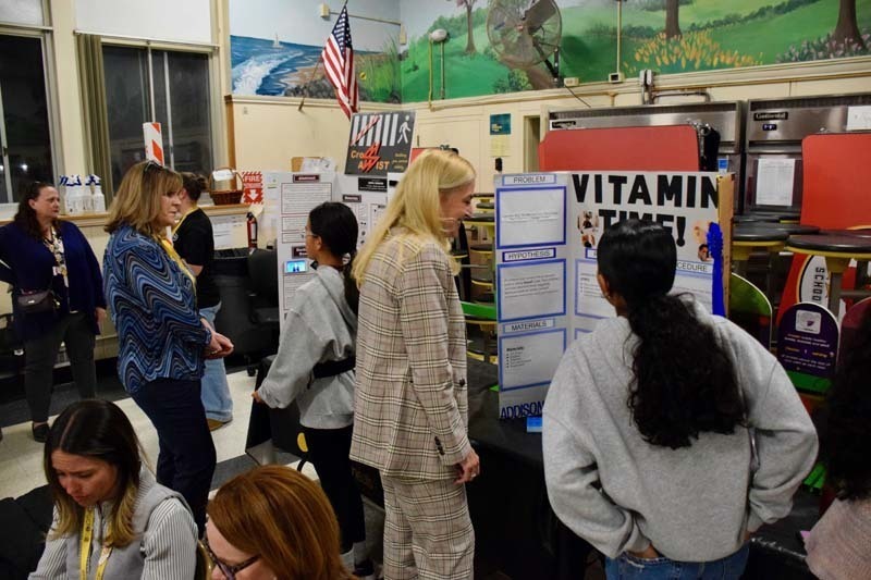 Students standing proudly in front of science fair projects.