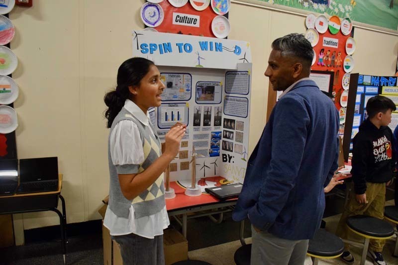 Students standing proudly in front of science fair projects.