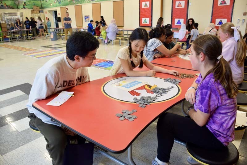 Teacher sitting at table with parent and student.