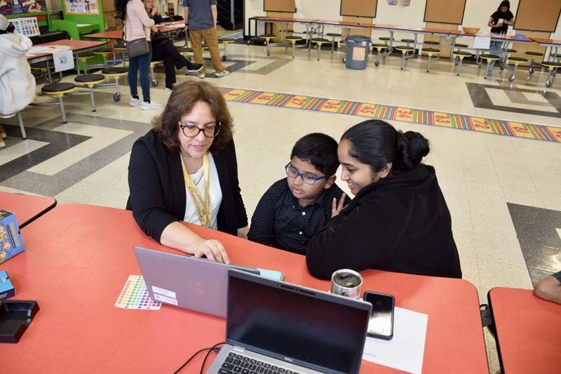 Teacher sitting at table with parent and student.