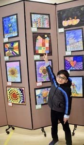Student standing proudly in front of art exhibit.