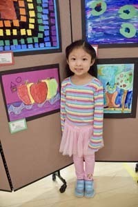 Student standing proudly in front of art exhibit.