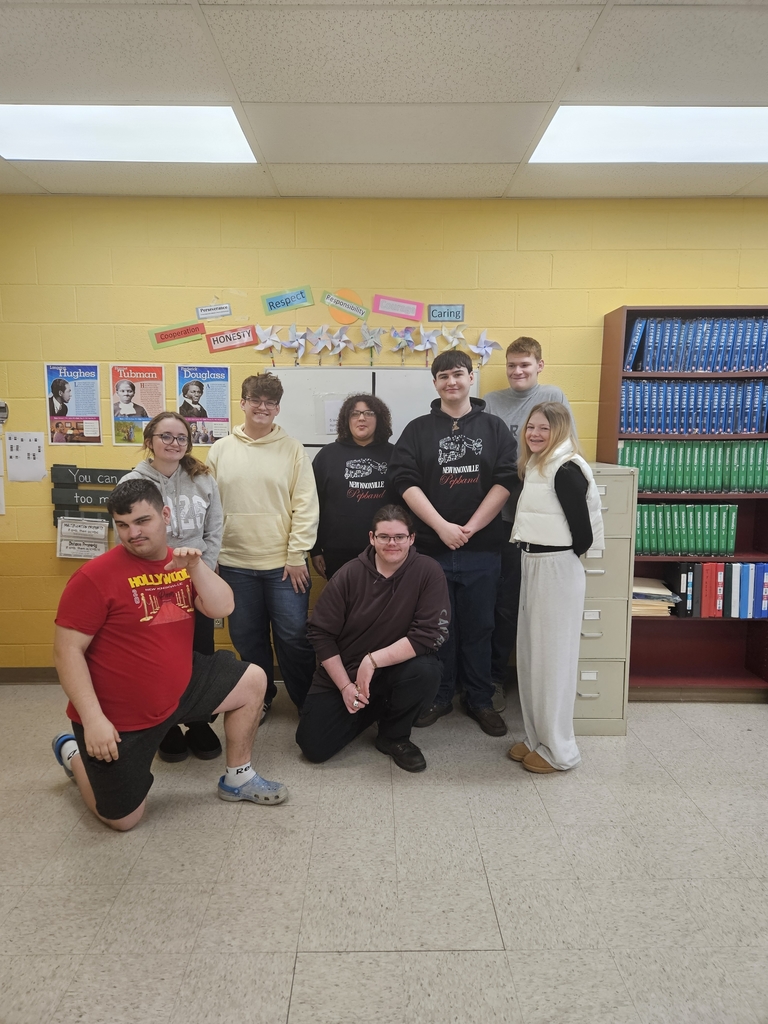 MMR Students pose below their pinwheel display which was a part of their logo design project.