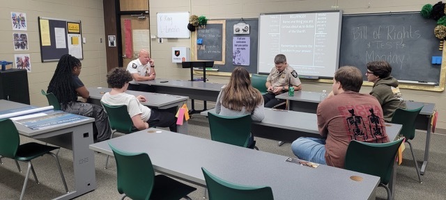 Students in a classroom listening to law enforcement