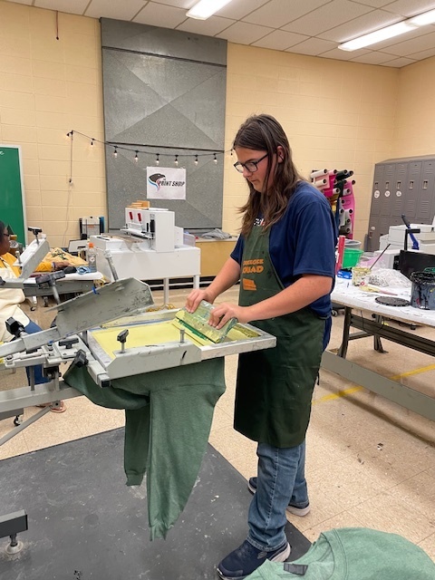 A student screen printing a shirt.