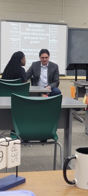A girl and a man sitting at the front of the classroom.