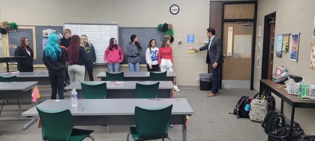 People standing at the front of a classroom.