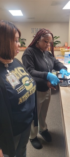 A female students fingerprinting a female adult.