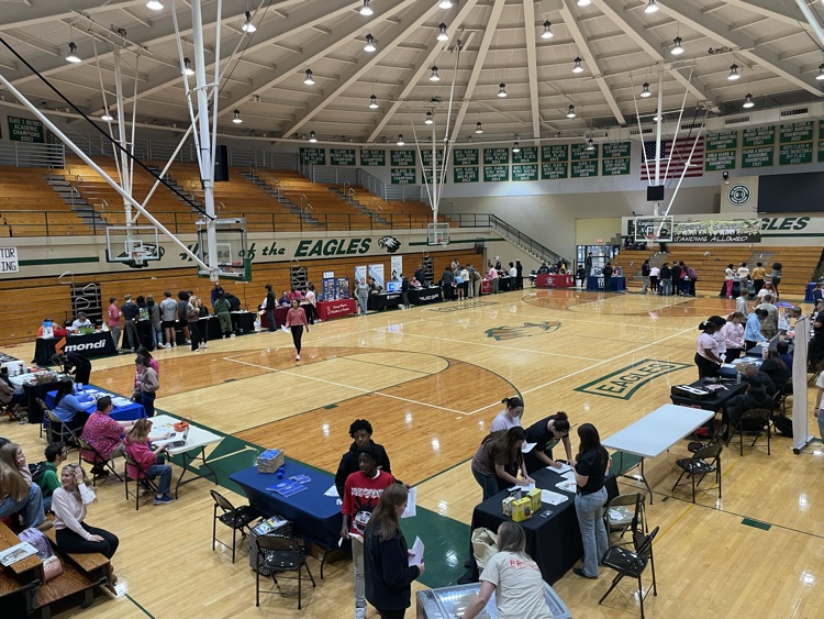 tables of businesses and students visiting the booths at a career fair