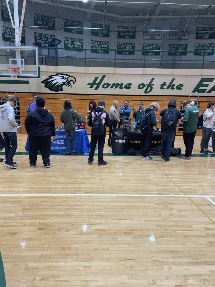 students in a gym talking to a business booth at a career fair