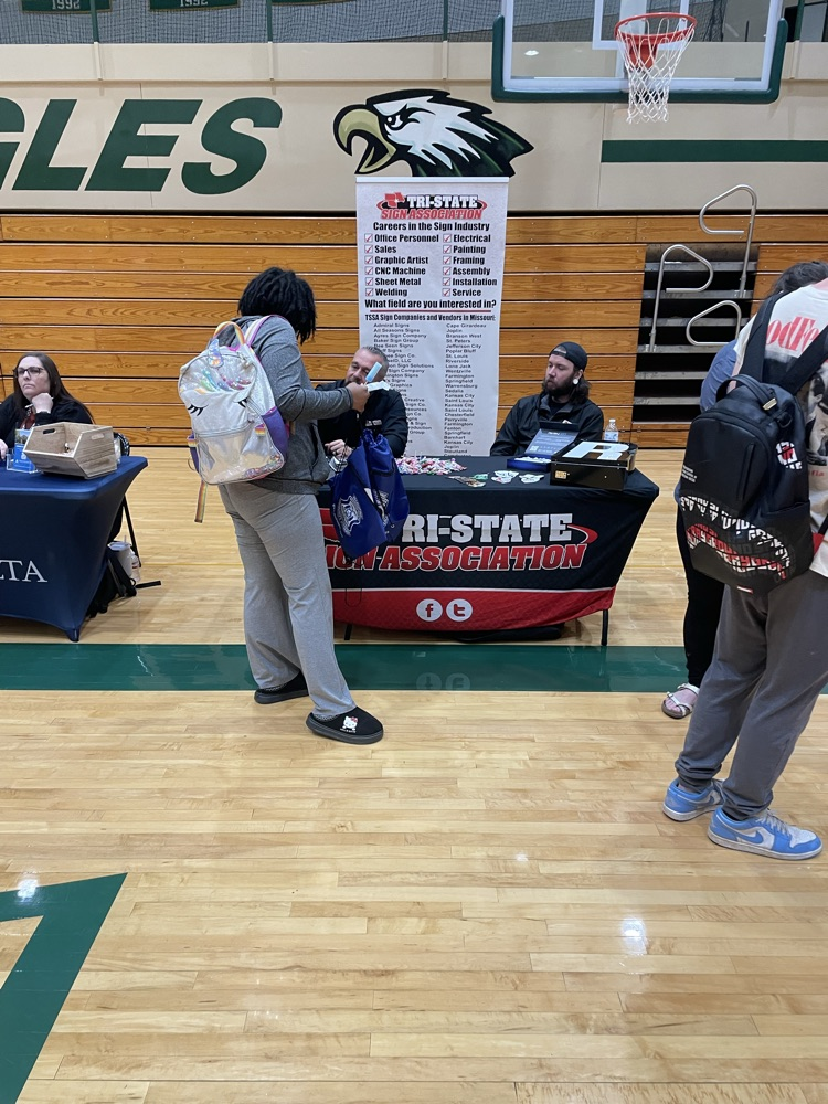 students talking to a printing company booth at a career fair