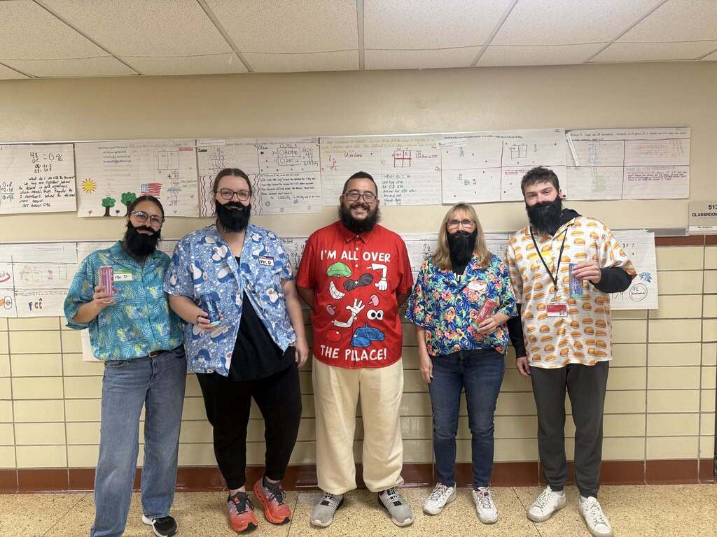 Our NRMS sixth grade teaching staff posing in a classroom with fake beards, Hawaiian-style shirts, and energy drinks.