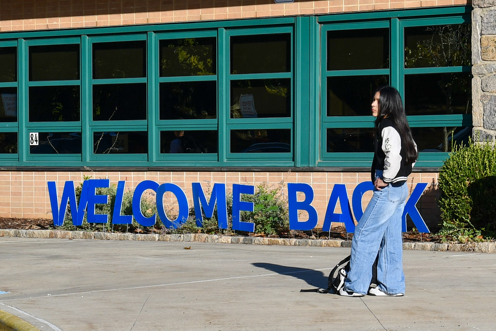 Welcome back to school sign with a student standing in front of it