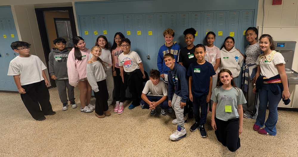 STudents pose for a photo in front of blue lockers with yellow sticky notes on them