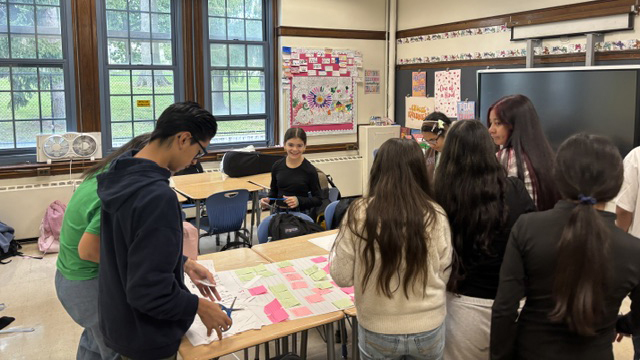 Students create sticky notes while working around a table