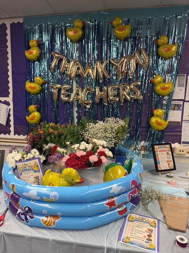 On a table, an inflatable pool (no water) holds a balloon duck, beachball, and a bunch of flowers. Behind it is 8 more balloon ducks and balloon letters spelling out: "Thank You Teachers".