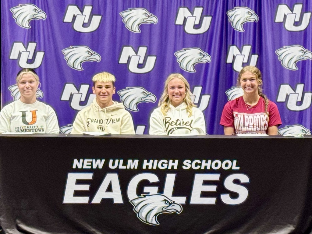 4 students siting behind a desk that says New Ulm High School Eagles, with the Eagle and NU logos behind them. The students' names are in the text of the post.