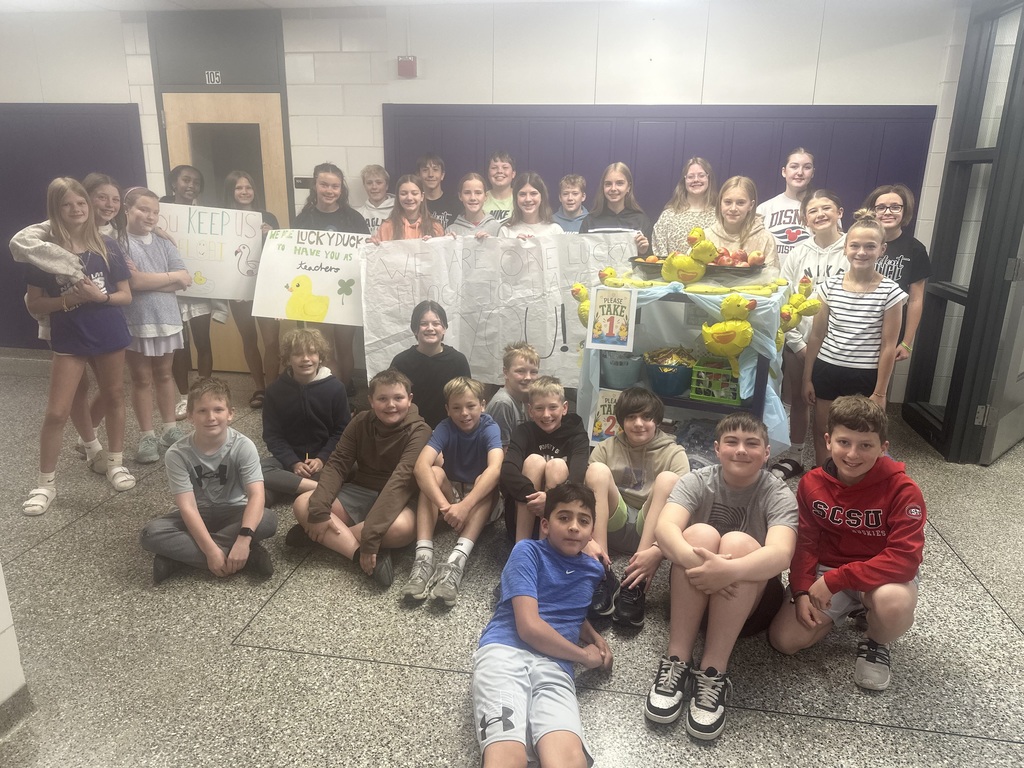 A group photo of all the MS students with their teacher appreciation signs and fruit/duck cart.