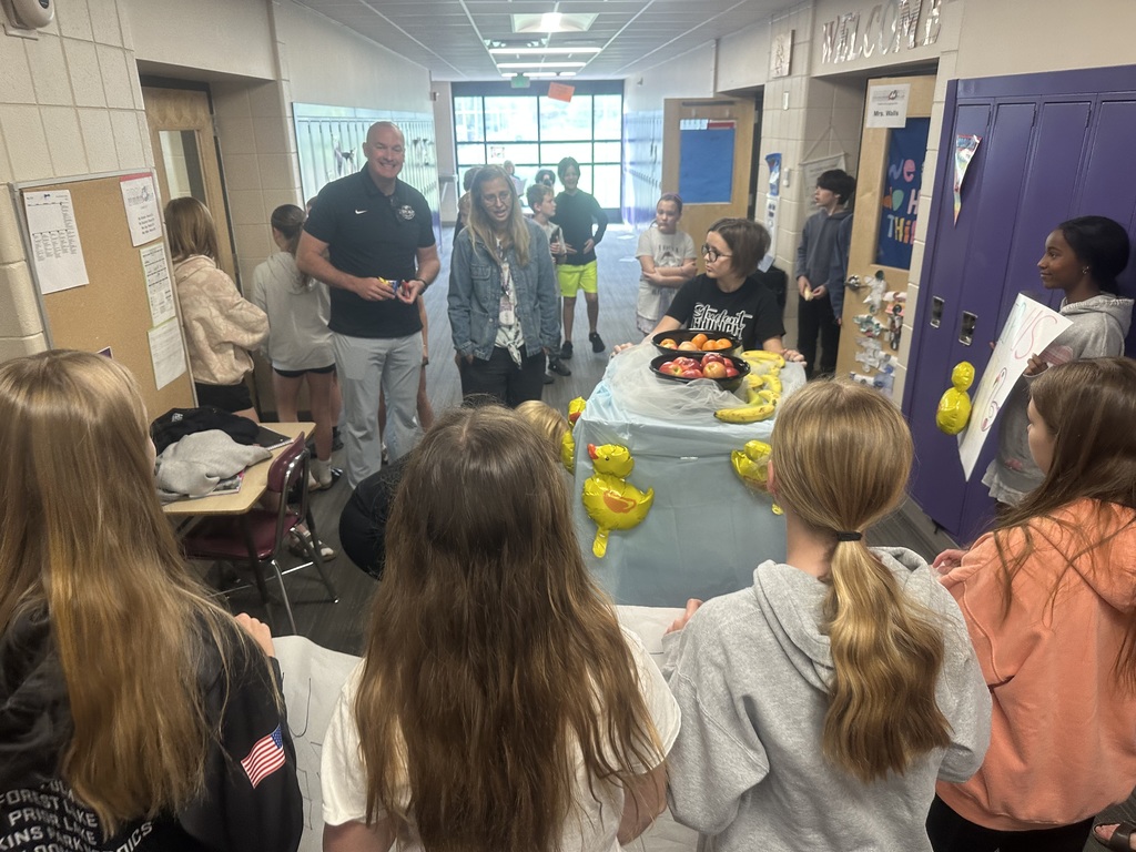 Students with their cart and teacher appreciation signs in a hallway, delivering fruit to more teachers